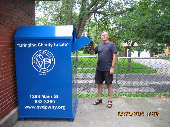 An image of a man standing next to a SVDP donation clothing bin.