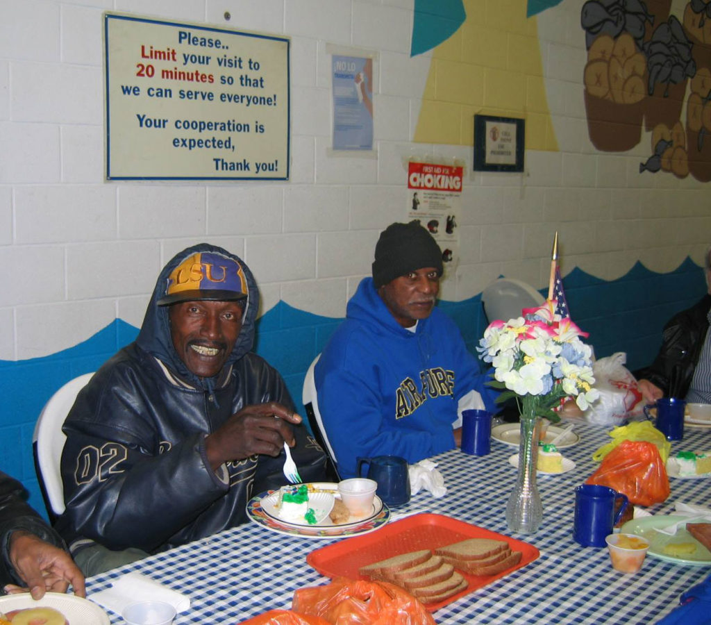 People smiling while eating in the SVDP Dining Hall.