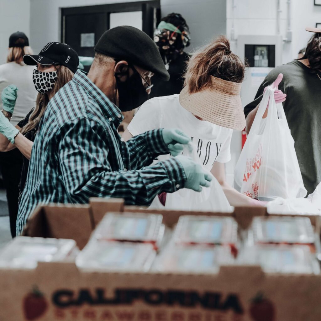 An image of people volunteering by helping pack food.
