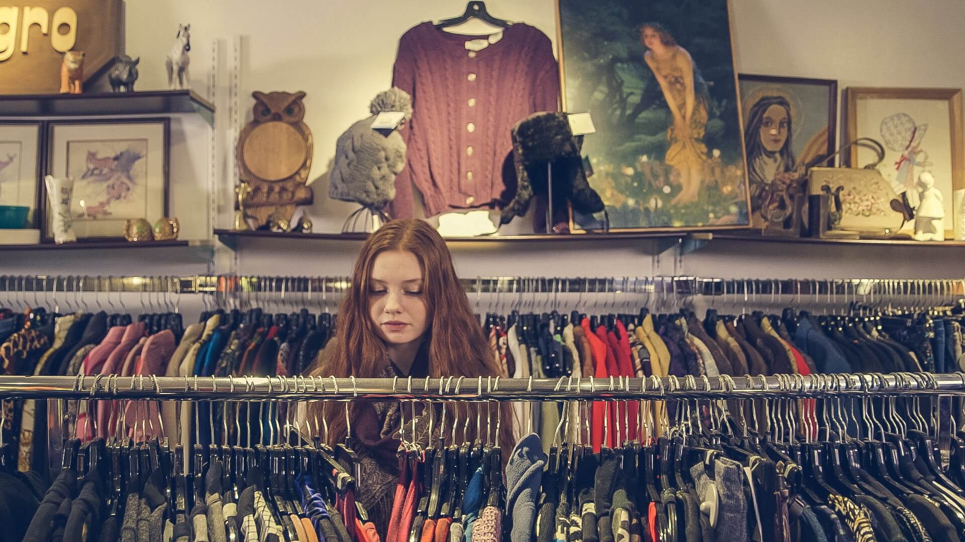 A women looking at a clothing rack in a thrift store.